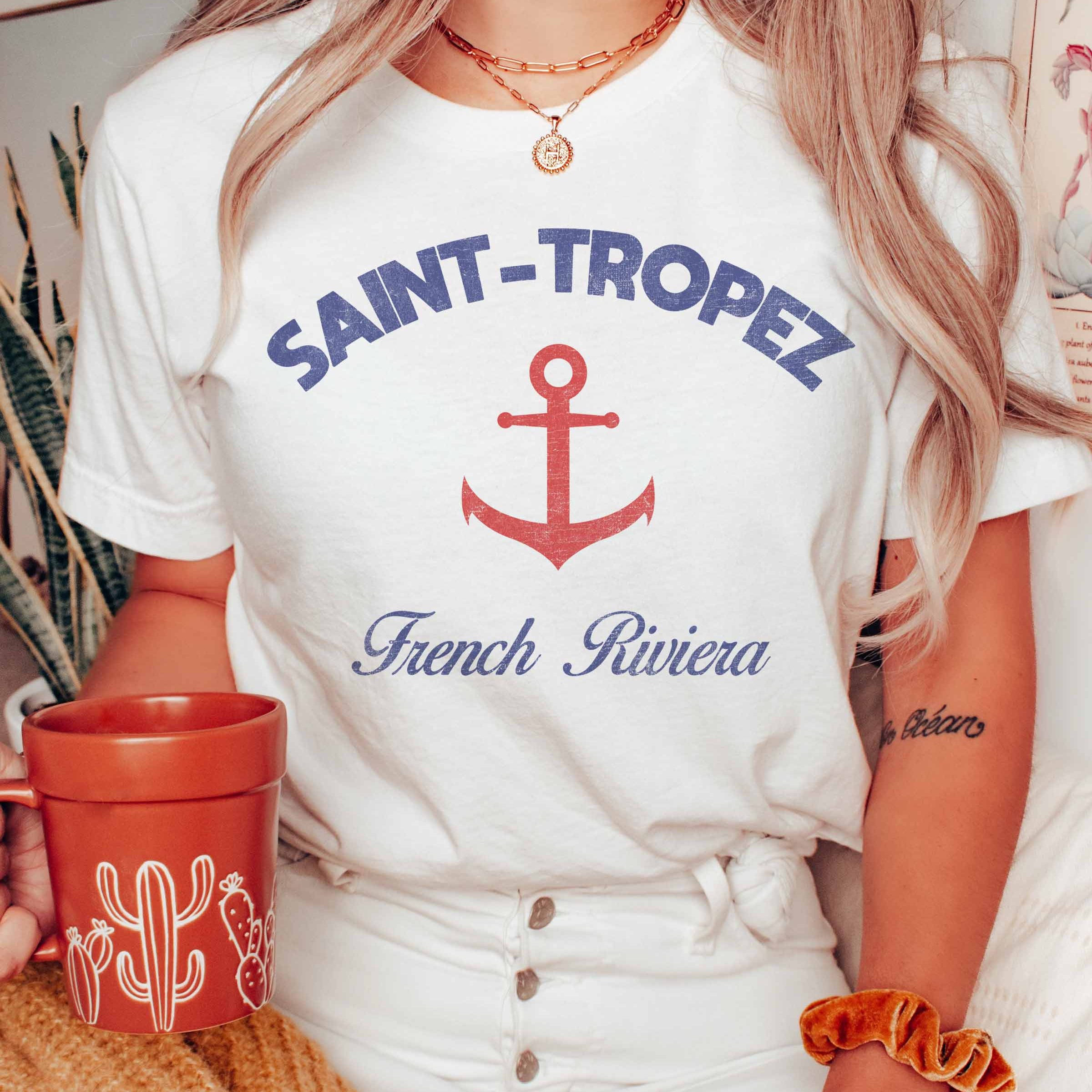 Saint Tropez Grafik-T-Shirt in Weiß mit Anker-Design und französischem Riviera Schriftzug, lässig getragen.